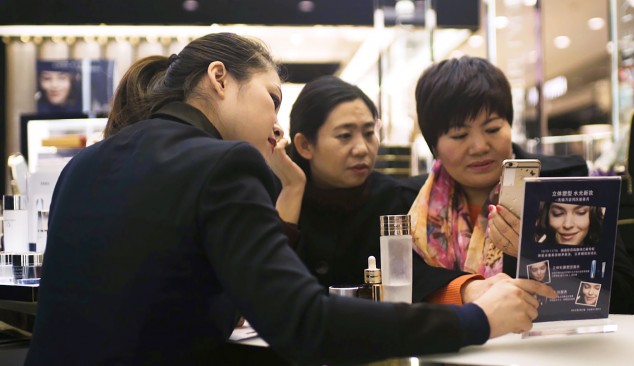 Китайские покупатели знакомятся с промо акцией, которую проводит Alibaba в магазине Estée Lauder