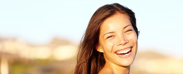 Summer woman portrait. Asian girl smiling happy laughing on beach vacation enjoying warm sunshine. Gorgeous mixed race Asian Chinese/ Caucasian female model outside.