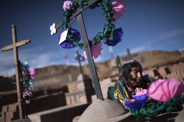 Женщина возлагает цветы на главном кладбище Сускеса