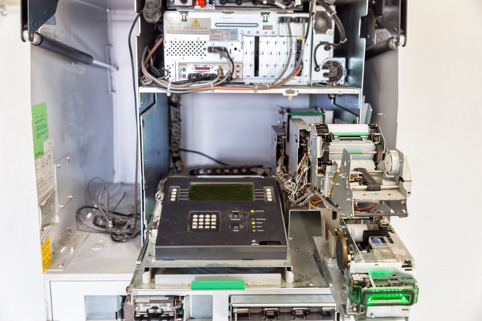 Довольно старый банкомат NCR 6676: наверху системный блок, под ним инженерная панель управления, справа карт-ридер с зелёной подсветкой