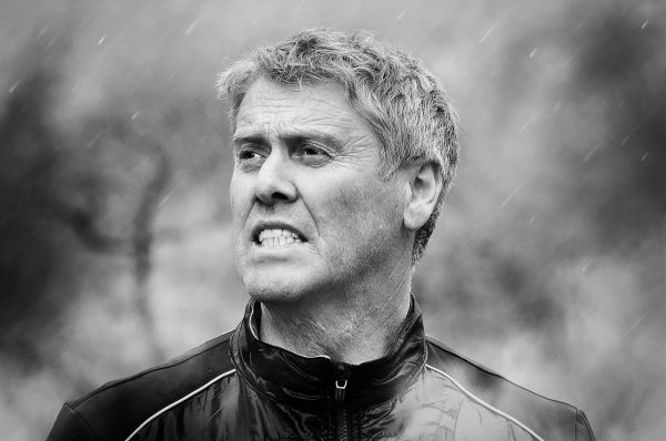 Мужчина среднего возраста напряжённо смотрит через дождь. Чёрно-белая фотография с размытым фоном.