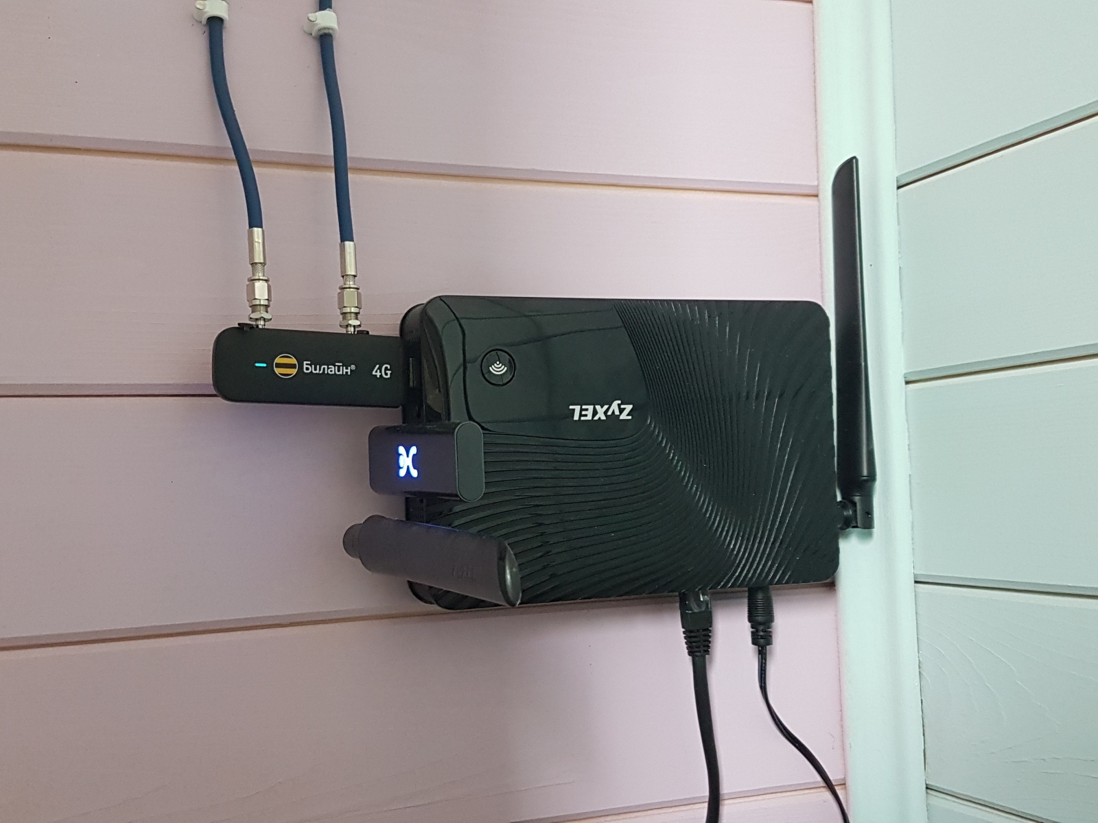 Роутер Zyxel с двумя USB-модемами, закрепленный на стене. К модему подключены провода от внешних антенн.