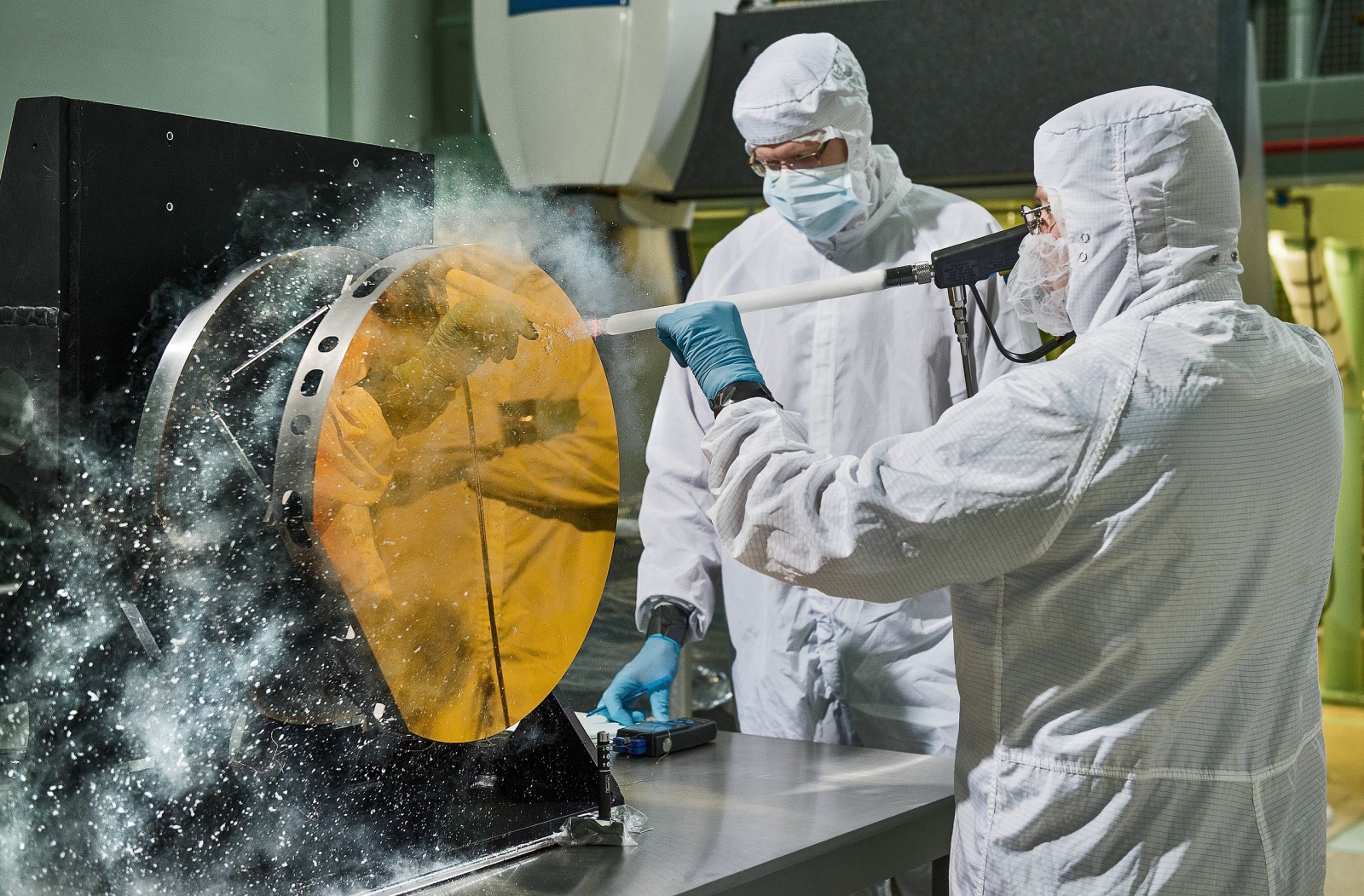 Инженеры в чистом помещении, чистят углекислым газом испытательное зеркало покрытое золотом в 2015 году