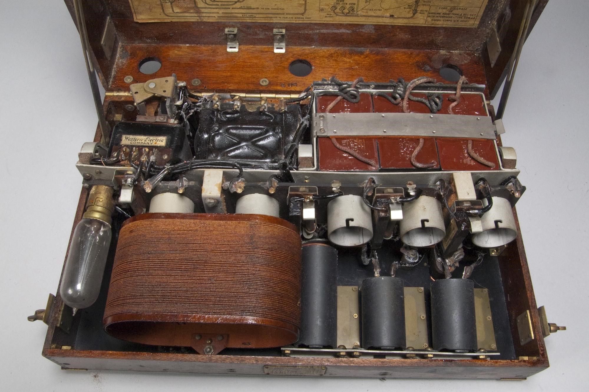 Главный блок трансивера Western Electric SCR 68, 1918 год, — первый военный радиотелефон. Слева вверху две батареи, справа от них — три конденсатора, в нижней части снимка отсек для ламп с шестью цоколями (пять рабочих ламп схемы усилителя и детектора, крайняя левая — балластная, устанавливалась не всегда), два из которых закрыты катушкой для экономии места. В глубине за цоколями ламп видны три чёрных регулировочных катушки. Этот трансивер — наглядный пример навесного монтажа, все элементы крепятся к корпусу и соединяются отдельными проводами. Такая методика сборки будет превалирующей вплоть до середины 1960-х / ©Smithsonian National Air and Space Museum