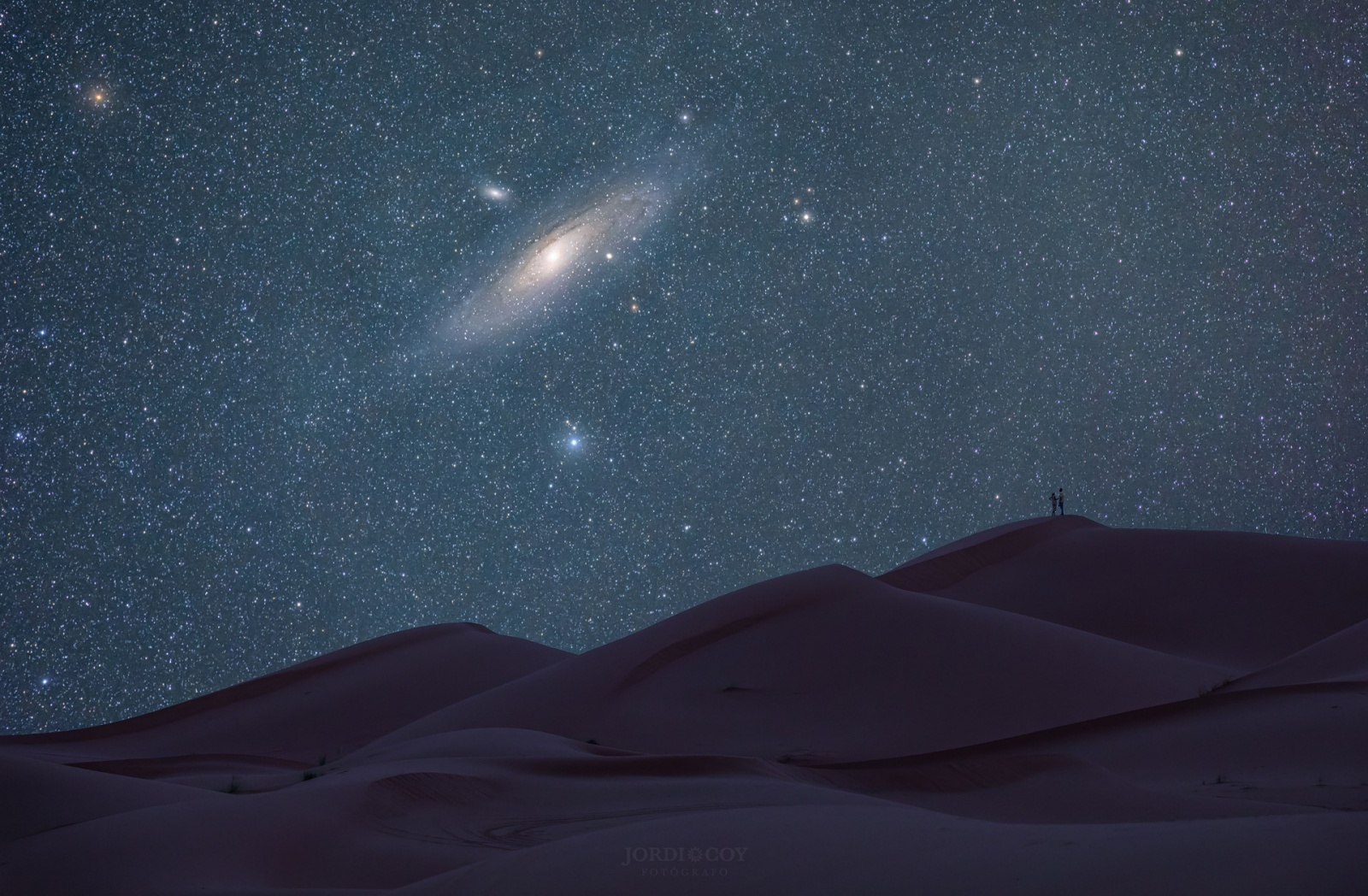 Галактики Андромеды заходит за барханы пустыни Сахара. Эта картинка не соответствует в точности видимости M31 из Южного полушария (ведь Сахара в северном). Но снимка этой галактики из Атакамы мне найти не удалось. Автор этого снимка Jordi Coy  