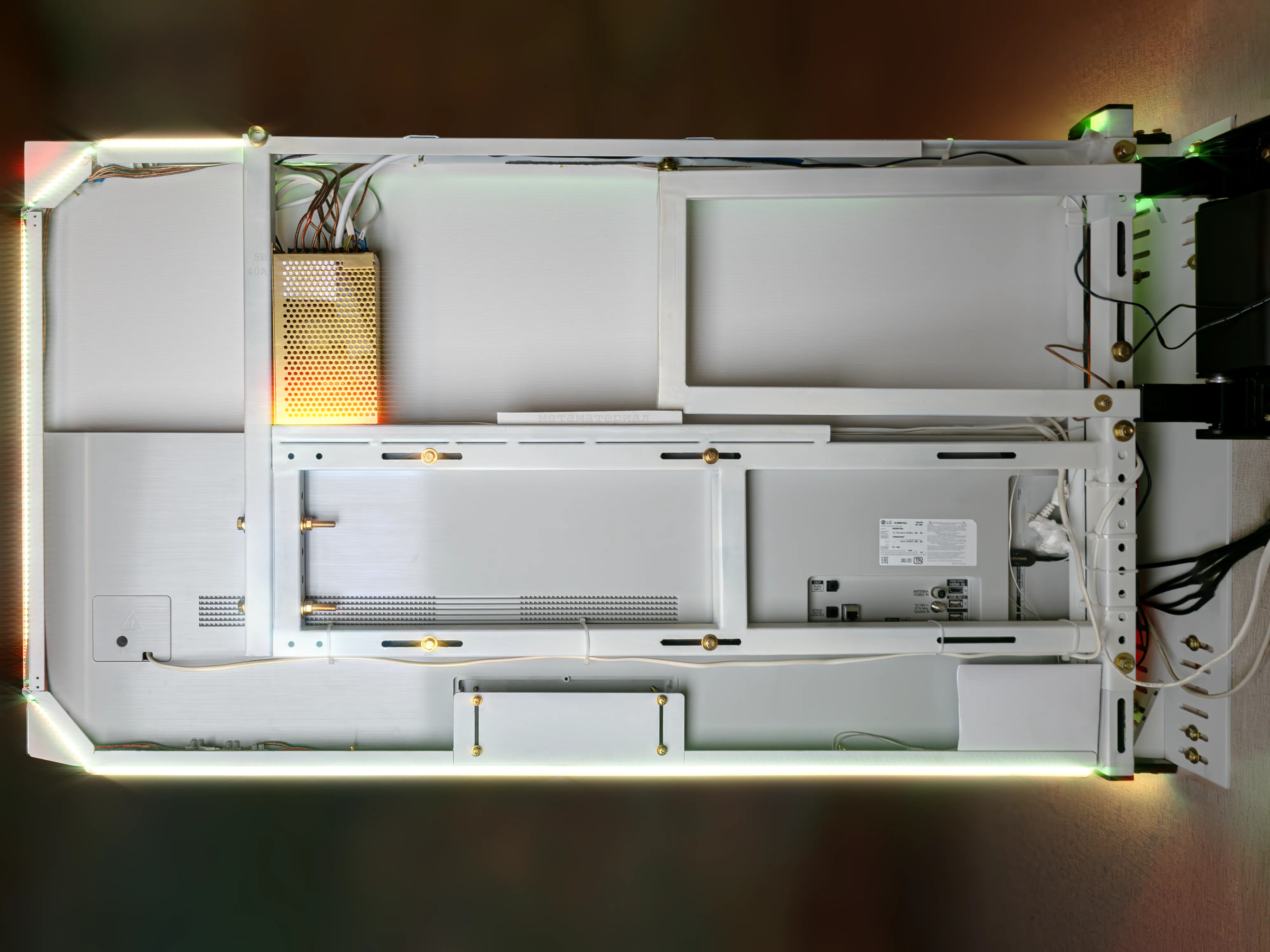 Правый телевизор открыт на 90°, вид сзади. Новый кронштейн не имеет вертикальных палок, поэтому нижний сегмент рамы подсветки просто прямой