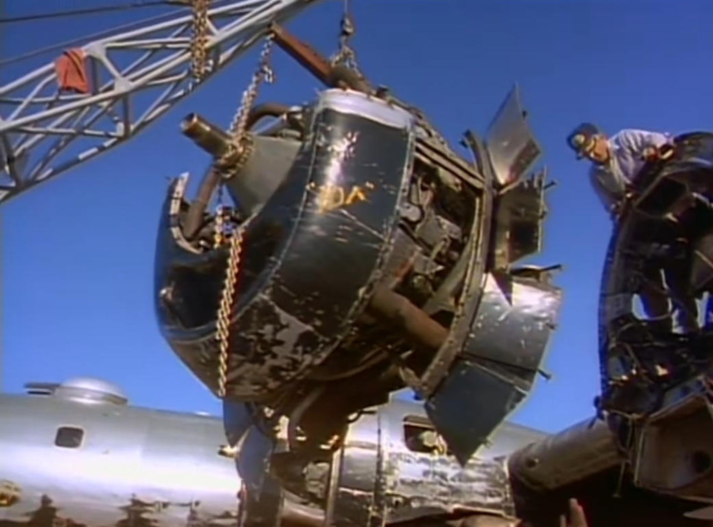 Снятие первого двигателя в начале августа. Хорошо видны черные створки системы воздушного охлаждения по периметру. Кран был построен Риком. Кадр из фильма «B-29 Frozen in Time» 