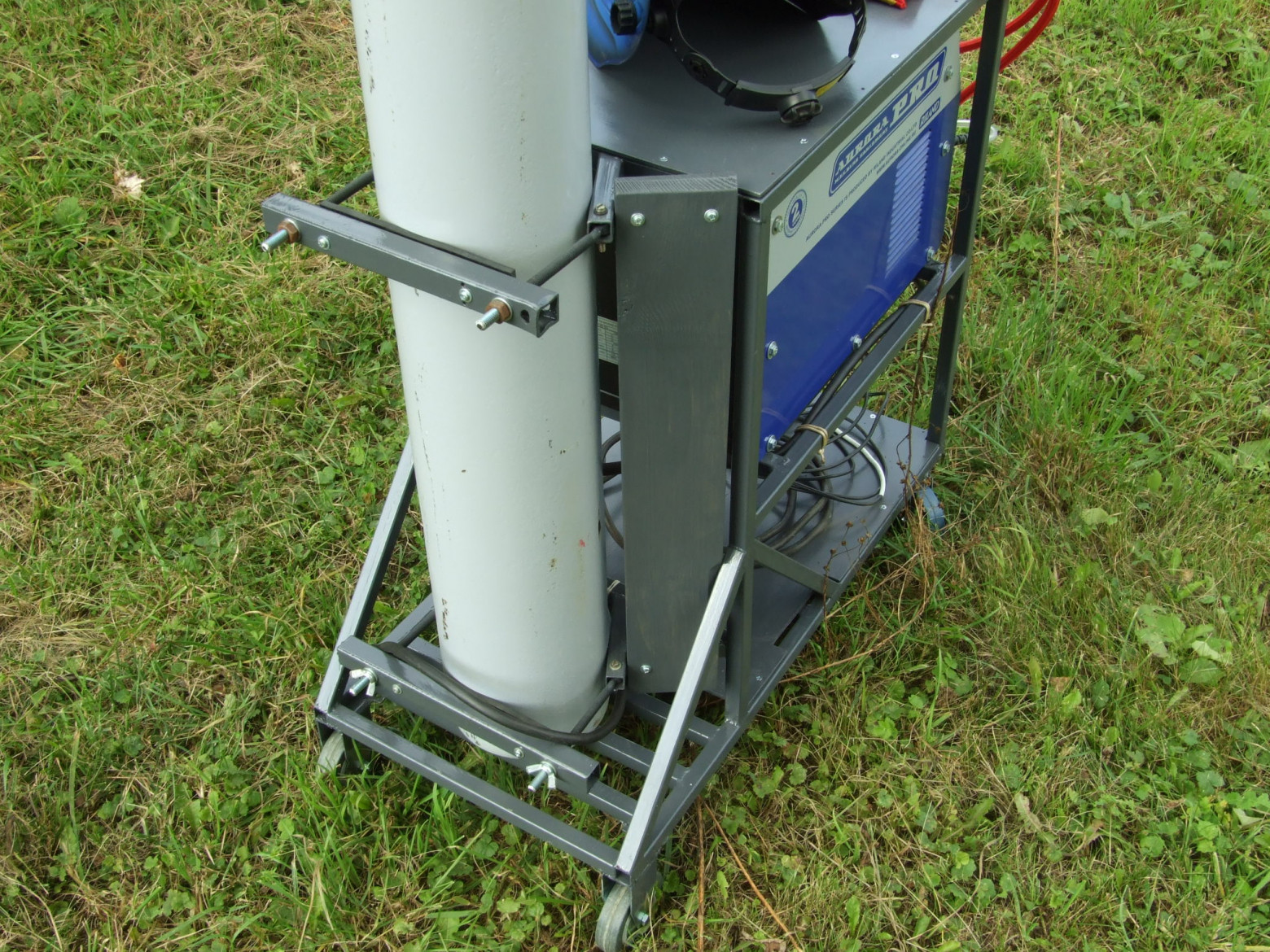 Фото 5.15. Пользуясь тёплой погодой, вырезал из строганной сосновой дощечки, подогнал, покрасил и установил площадку для потенциального электрического удлинителя на четыре розетки — сварочный аппарат, вероятный блок водяного охлаждения, местное освещение. Видна конструкция крепежа баллона