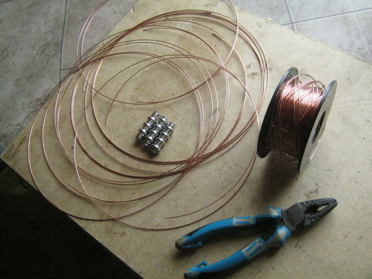 Фото 6.1. Моё самодельное приспособление для облегчения подачи присадочного прутка [1] позволяет нормально работать и с нетолстой проволокой при сварке мелочей и тонкостенных деталей. На фото — подготовка стальной омеднённой проволоки Ø 1 мм с катушки для сварки полуавтоматической. В центре — приспособление для выравнивания