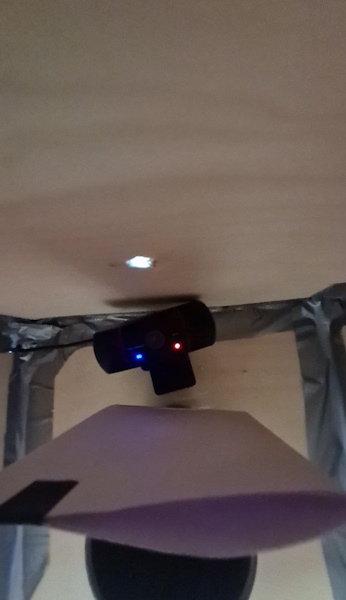 Внутри демонстрационного стенда: отверстие, через которое проходит свет, формирующий изображение; белый лист бумаги, выполняющий функции матрицы камеры, на нём формируется изображение; USB‑камера для получения изображения с листа бумаги.