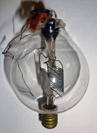 Фото 2.2. Аудион де Фореста. В ранних моделях сетка и анод были только с одной стороны, а вольфрамовых нитей две — быстро перегорали в низком вакууме. Здесь нить накала единственная, вероятно, платиновая. Анод — никелевые пластинки, сетки — грубые проволочные зигзаги. В радиоприёмнике Аудион обычно крепился вверх цоколем для лучшего положения висящей нити накала