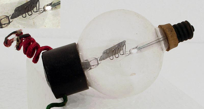 Фото 2.2. Очень ранний вариант коммерческого «клапана» Ли де Фореста — Аудион. Как и все тогдашние лампы, имел низкий вакуум. Нити накаливания из тантала, вторая — резервная. Анод — небольшая пластинка из никеля. Рабочее положение прибора — вверх винтовым цоколем, чтобы нити не изогнулись и не упали на сетку. Сетка — грубая проволочная загогулина