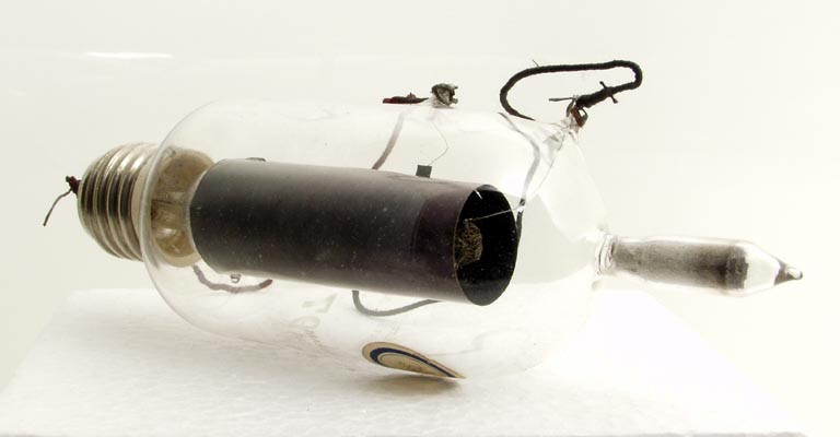 Фото 2.4. Британский «мягкий» (газонаполненный) триод N-типа 1914…1915 годов. Несомненный наследник конструкции клапана Флеминга. Имеет платиново-иридиевую нить накала и стеклянный отросток, наполненный асбестом для регулирования (нагревом отростка) оптимального давления в колбе. В приёмнике Marconi Type 27 лампа использовалась как высокочастотный усилитель. Этот приёмник работал в диапазоне от 60 до 500 кГц. Ионные (с газом или невысоким вакуумом) лампы были чрезвычайно капризные в эксплуатации, требующие настоящего искусства в обращении с ними, что привело к изобретению ламп высоковакуумных, «жёстких» — стабильных и не требующих высокой квалификации радиста