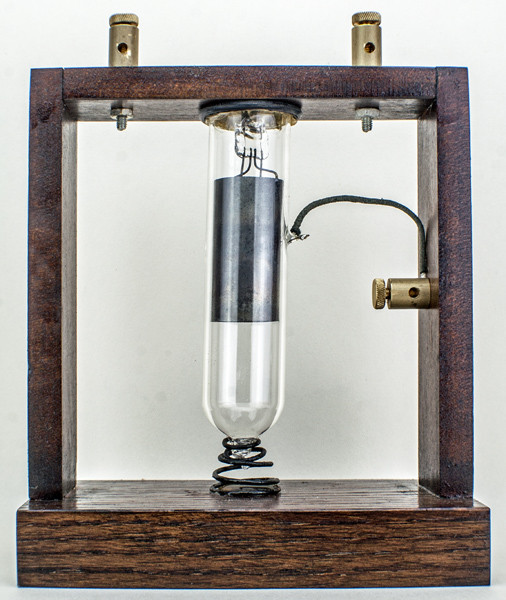 Фото 1.3. Ещё один из экспериментальных, как их тогда называли — клапанов, Флеминга, в новодельном деревянном каркасе. Судя по более тщательному исполнению трубки (лампы), эксперименты не первые. Нить накала в первых трубках Флеминга была угольной, работающей от напряжения 12 вольт. В более поздних вариантах она стала классической — металлической вольфрамовой и работала от 4 вольтовой батареи через реостат для компенсации постепенного разряда