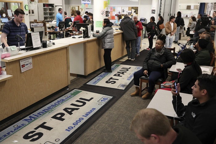 A crowd of people wait to be helped at the department of vehicle services, which is decorated by large floor mats of St Paul Minneosta license plates.