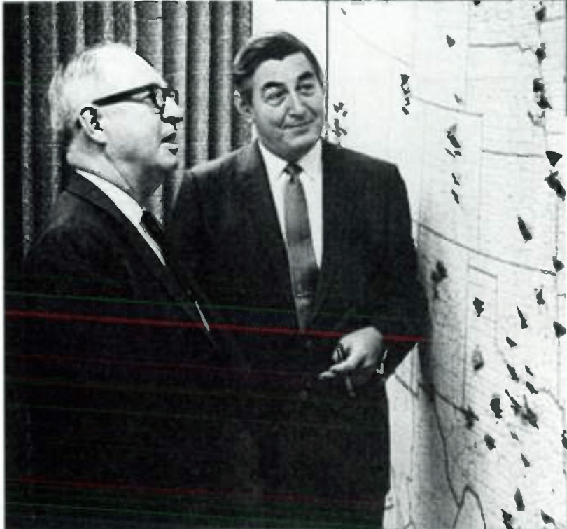 Тэнди (справа) с другим руководителем и его фирменной сигарой перед картой местоположений Radio Shack [Ирвин Фармин, Tandy's Money Machine , фотовставка].