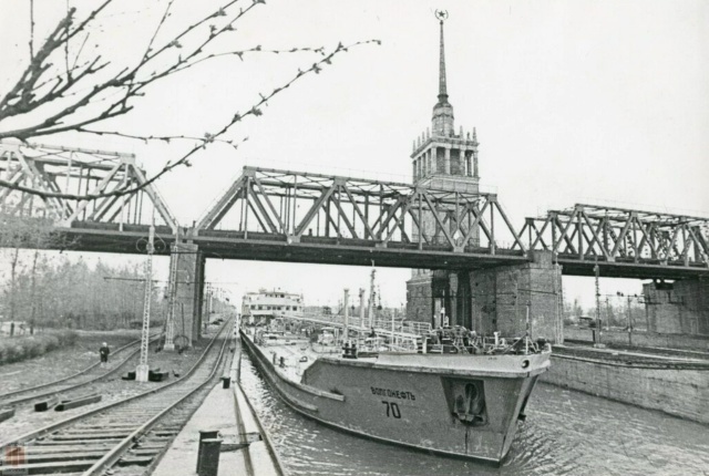 Танкер «Волгонефть-70» проходит под плотинными мостами, 1980 г. А за мостами притаилась визитная карточка шлюзов — башня «Камводпути». Источник