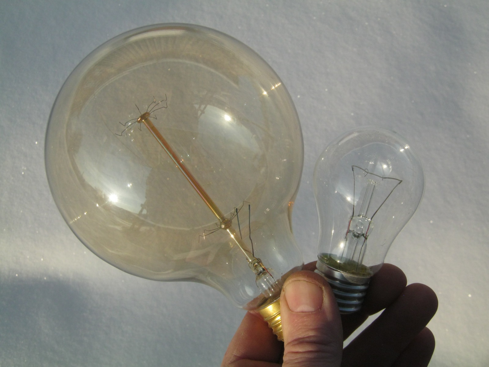 Фото 5.1. При заводском крупносерийном изготовлении ЛН дозировать количество фосфорного геттера стараются возможно более точно — при его недостатке срок службы ламп снижается, при избытке же, непрореагировавший фосфор сам образует на колбе красноватый налёт, ухудшая световые характеристики лампы. На фото — две новых ЛН — обычная осветительная 100-ваттная «груша» и крупная новодельная «лампа Эдисона» китайского производства. Фосфор в последней явно отмеряли щедрой рукой. Большой беды здесь, однако, нет — лампа это скорее декоративная, нежели осветительная