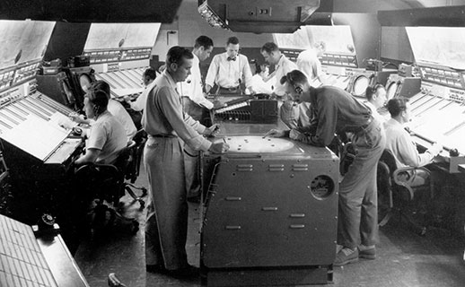 Станция управления воздушным движением, 60е годы. В середине стоит большой экран радара по которому операторы вручную двигают пластиковые "уточки" отмечающие положение самолетов