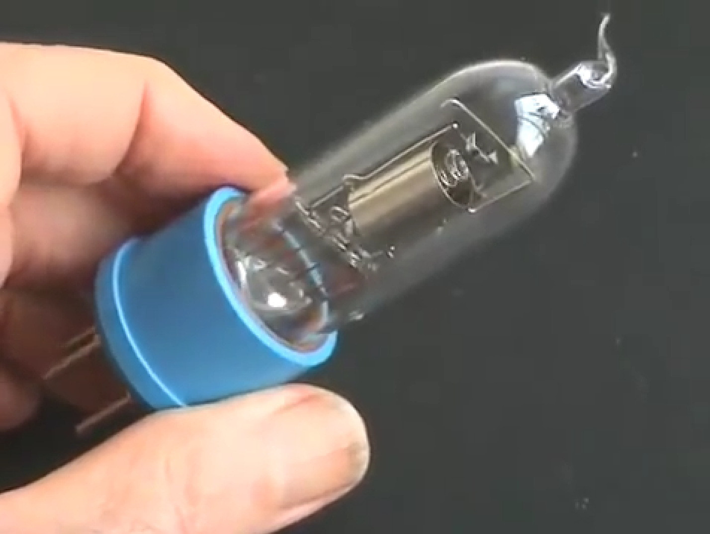 Фото 4.1. Вариант триода ТМ коллеги Клода Пайяра. Лампа высоковакуумная, с вертикальным расположением анода, применён оригинальный металлический геттер. Прямой накал из чистого вольфрама, цилиндрический «блестящий» — без чернения, анод из листового никеля, из никелевой же нетолстой проволоки — траверсы и спиральная сетка, крохотная молибденовая пружинка-удочка — отрезок проволоки сверху, поддерживает натяжение нити накала, компенсируя её удлинение при разогреве. Колба из легкоплавкого стекла платиновой группы [7], соответственно — впаи из электровакуумного спецбиметалла — платинита. Конструкция колбы лампы — с гребешковой ножкой. Стеклянная часть снабжена самодельным пластиковым четырёхштырьковым цоколем исторического типа