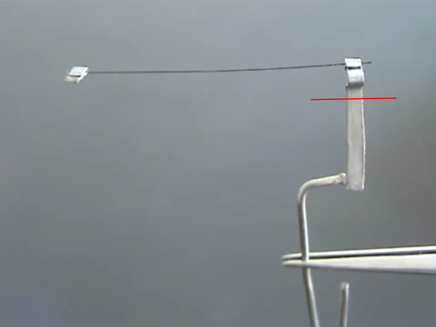 Фото 4.5. Заготовка прямонакального вольфрамового катода. W нить выровнена, отмерена, её концы зажаты в пистонах для приваривания. V-образная загогулина на необрезанном конце — нижний радиатор