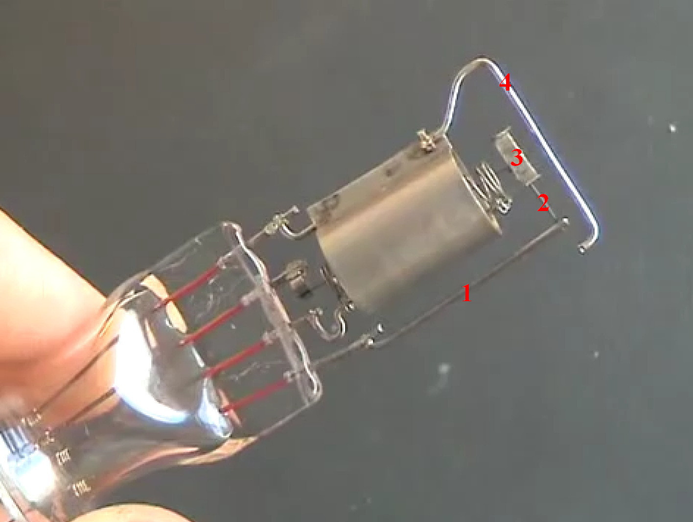 Фото 4.8. Ножка лампы с электродной системой в сборе — приварена траверса 1 для верхнего конца нити, с Мо пружиной-удочкой 2 и П-образным Ni радиатором 3 на её конце. К радиатору, с предварительным натяжением пружины, приварен верхний конец нити в пистоне. На аноде смонтирована перекладина-распорка 4