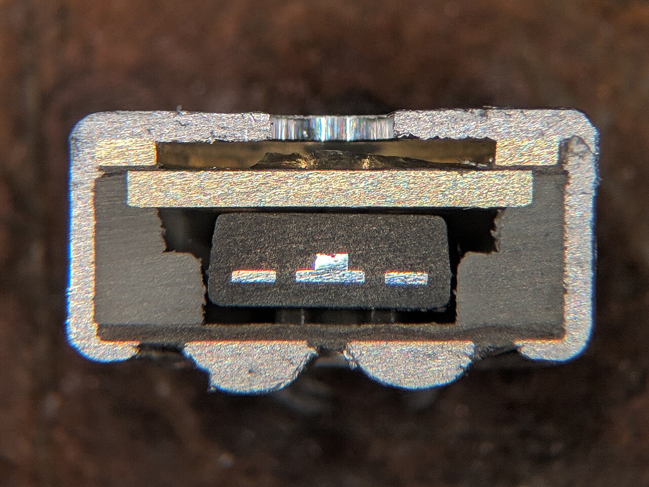 Распиленный поперек капсюль, видны три электрода и кристалл транзистора. Фото: TubeTimeUS, wikimedia