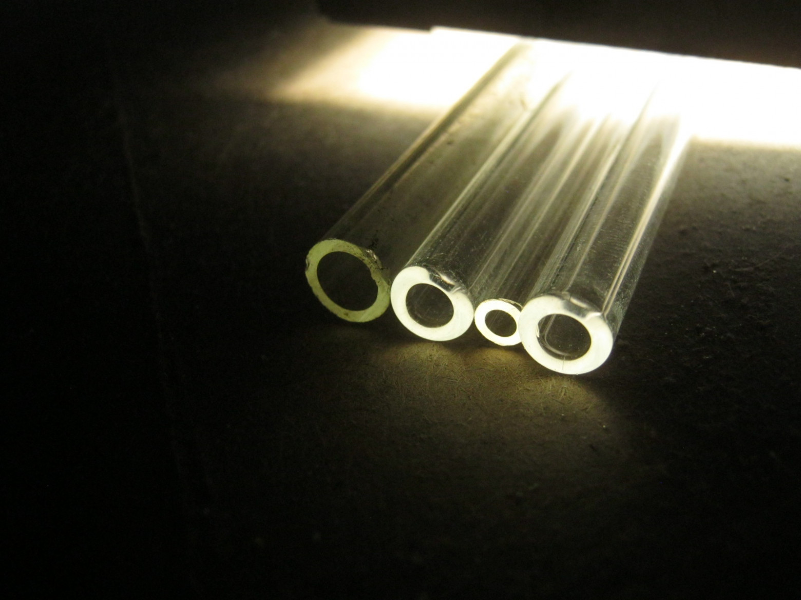 Фото 3.5. Три трубочки из современного «боросиликатного 3.3» стекла и одна из старого советского пирекса. Дополнительный признак стёкол вольфрамовой группы — их тугоплавкость — в газовоздушном, без примеси кислорода в дутье, пламени, толком размягчить их невозможно. При пайке (сильном, до текучести разогреве), боросиликатного стекла, оно ослепительно светится, так что обычные неодимовые (дидимовые) защитные очки, для такой работы приходится применять с дополнительным затемнением