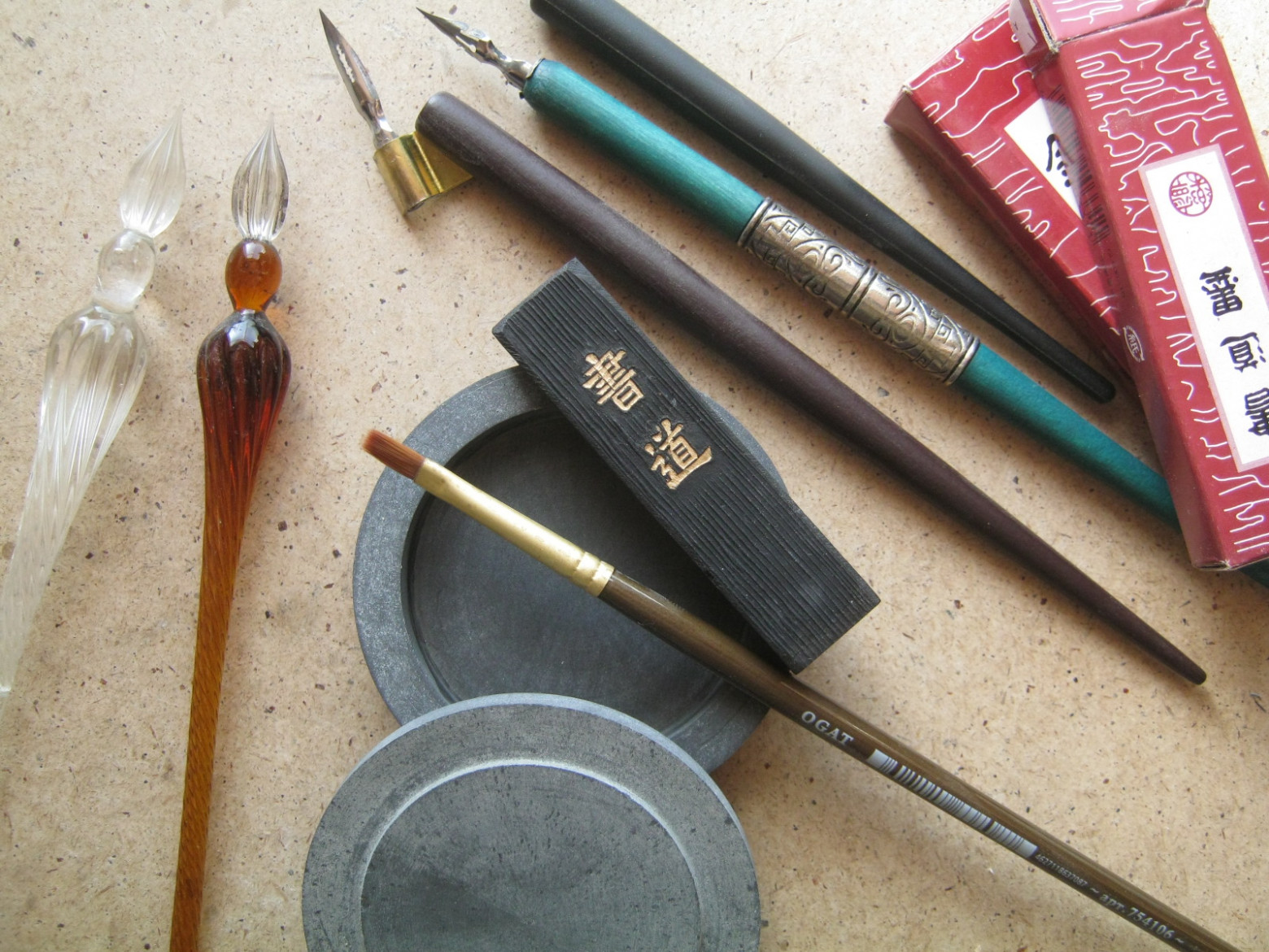 Фото 2.1. Традиционная китайская тушь изготовляется из сажи, получаемой и собираемой от сгорания хвойной смолы, растительного или животного жира, смешиваемой с костным или рыбьим клеем. Густой состав формуется в брусочки и тщательно высушивается. Для приготовления порции жидкой туши, такой брусок (в центре фото) растирается в специальном корытце — тушечнице из мелкопористого камня, с толикой воды. Приготовленная тушь может быть использована не только для традиционной восточной каллиграфии кистями, но и для живописи, для письма стальными или деревянными (тростниковыми — калям) перьями