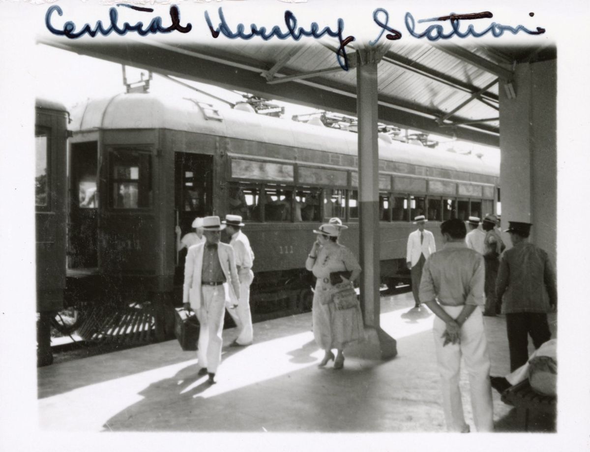 Шоколадно-электрическая железная дорога на Кубе - 1 Black and white photo of a train station platform, with people on it.