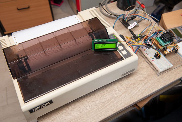Photograph of a dot matrix printer with, to the right, a prototype electronics circuit with many wires.
