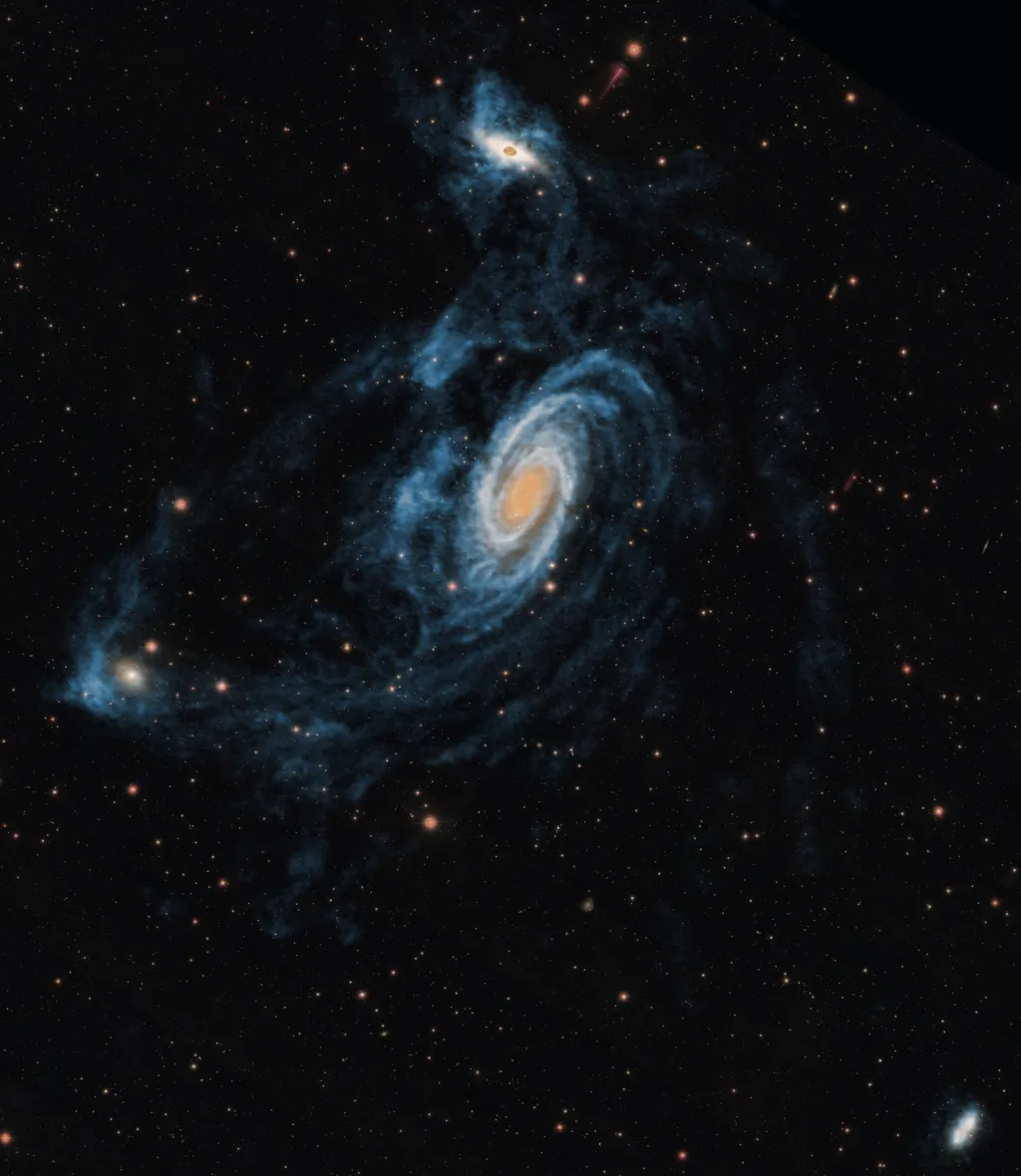 Триплет M81, состоящий из M81 (справа по центру), M82 (сверху) и NGC 3077 (слева), соединен обширным мостом из нейтрального водорода. Снижение объема газа, звездообразование и гравитационные приливные эффекты взаимосвязаны, причем сила приливных сил возрастает гораздо быстрее с уменьшением расстояния, чем даже гравитационная сила. В конечном итоге все три эти галактики должны слиться. Источник: Blok et al. 2018, ApJ